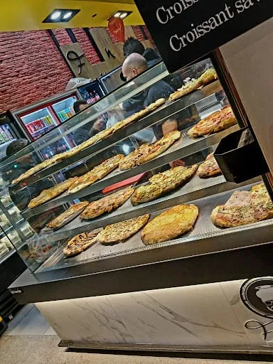 Η βιτρίνα με τις πίτσες και τα κρουασάν, μπροστά στον τούβλινο τοίχο.